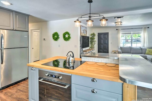 kitchen featuring gray cabinetry, hanging light fixtures, dark wood-type flooring, stainless steel appliances, and wood counters