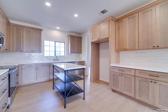 kitchen with sink, tasteful backsplash, stainless steel appliances, and light hardwood / wood-style flooring