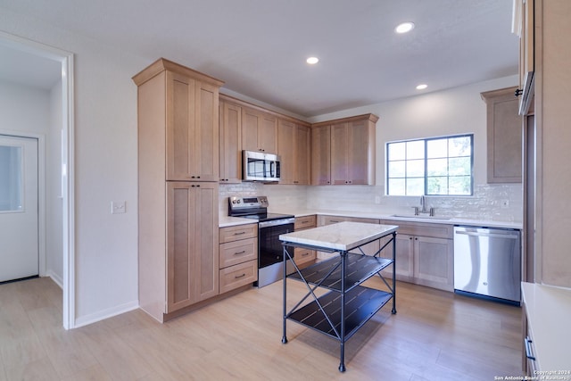 kitchen with backsplash, sink, stainless steel appliances, and light hardwood / wood-style floors