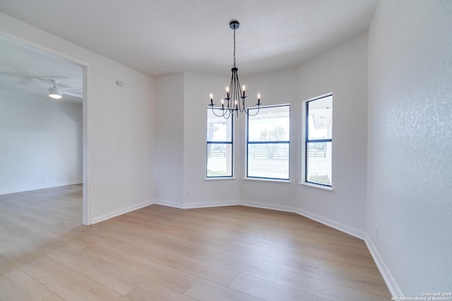 unfurnished room with ceiling fan with notable chandelier and light hardwood / wood-style flooring