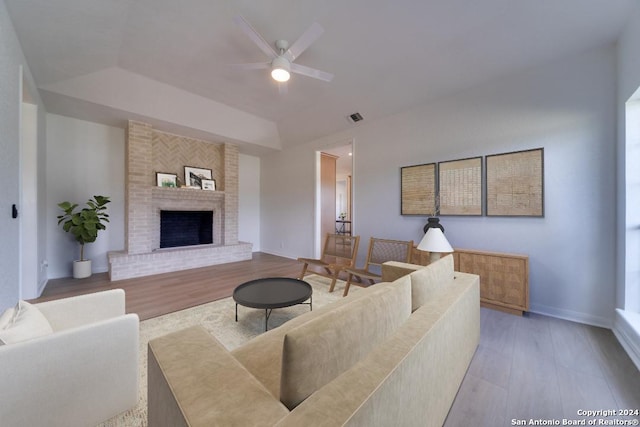 living room with a fireplace, light wood-type flooring, and ceiling fan