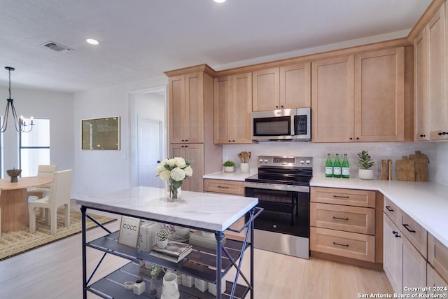 kitchen featuring backsplash, decorative light fixtures, light wood-type flooring, a notable chandelier, and stainless steel appliances