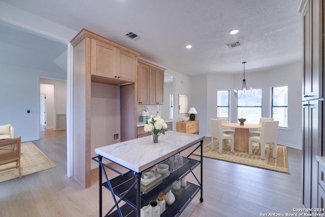 kitchen featuring light brown cabinets, decorative light fixtures, light hardwood / wood-style flooring, and a notable chandelier