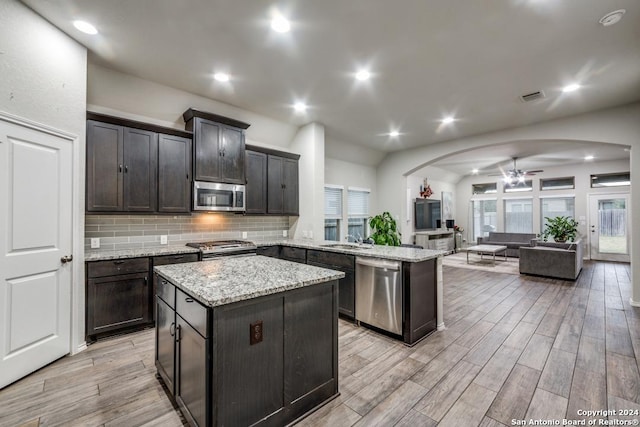 kitchen with a center island, ceiling fan, light wood-type flooring, appliances with stainless steel finishes, and kitchen peninsula