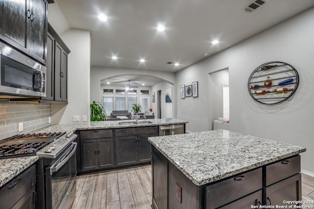 kitchen featuring backsplash, a center island, stainless steel appliances, and light wood-type flooring