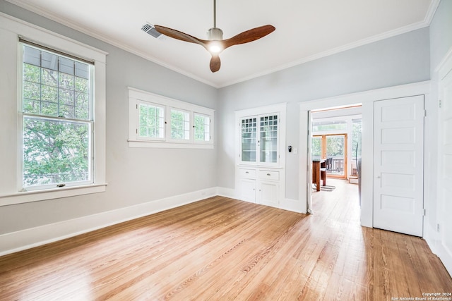 empty room with ceiling fan, ornamental molding, a healthy amount of sunlight, and light hardwood / wood-style floors