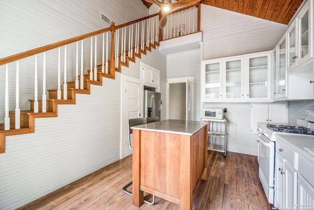 kitchen featuring a center island, a high ceiling, white range with gas stovetop, hardwood / wood-style floors, and white cabinets