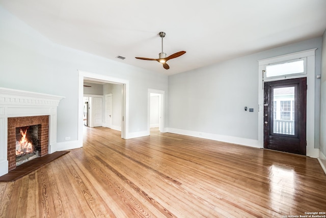 unfurnished living room featuring ceiling fan, wood-type flooring, and a fireplace