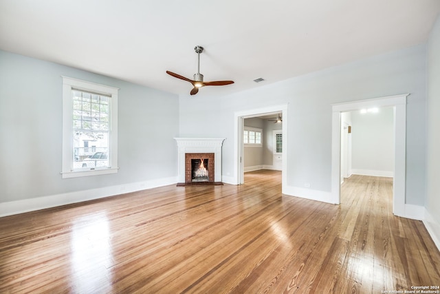 unfurnished living room featuring a brick fireplace, ceiling fan, and light hardwood / wood-style flooring