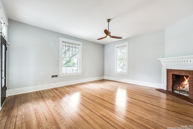 unfurnished living room with ceiling fan, light wood-type flooring, and a fireplace