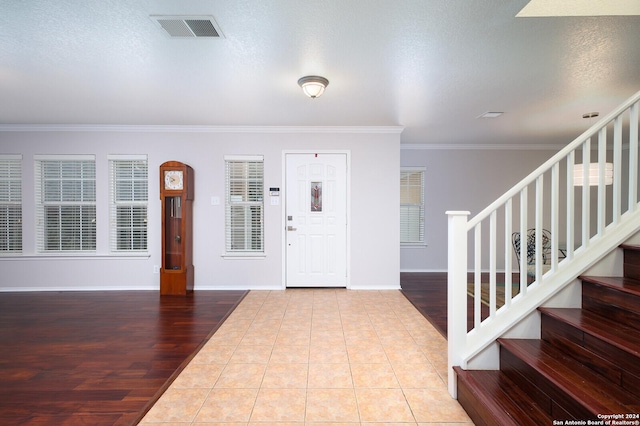 foyer entrance with a textured ceiling, wood-type flooring, and crown molding