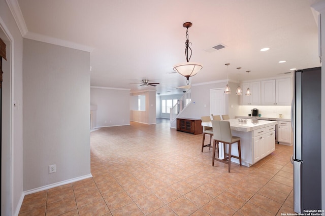 kitchen with pendant lighting, a center island, ceiling fan, white cabinetry, and stainless steel refrigerator