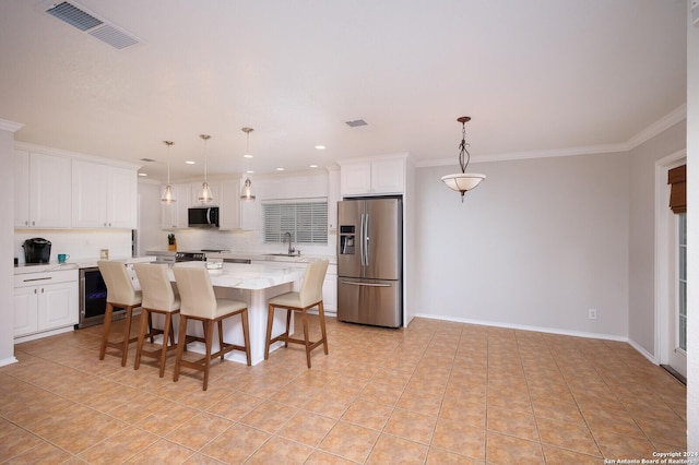 kitchen with a breakfast bar, stainless steel appliances, white cabinets, a kitchen island, and hanging light fixtures