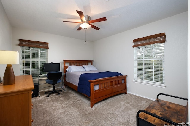 bedroom with ceiling fan, light carpet, and multiple windows