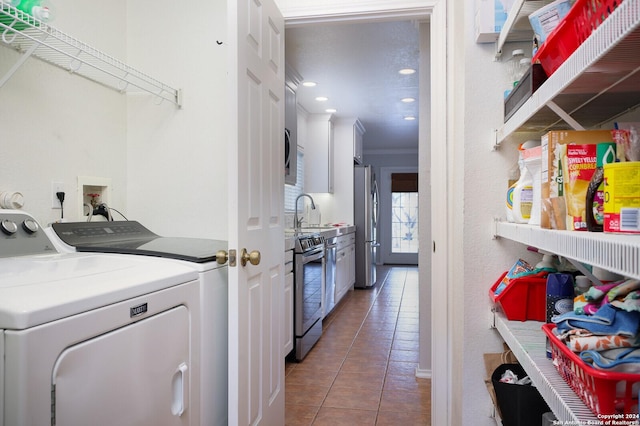 clothes washing area featuring washing machine and dryer, tile patterned floors, ornamental molding, and sink