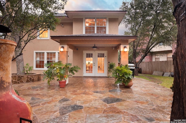 back house at dusk with french doors, ceiling fan, and a patio area