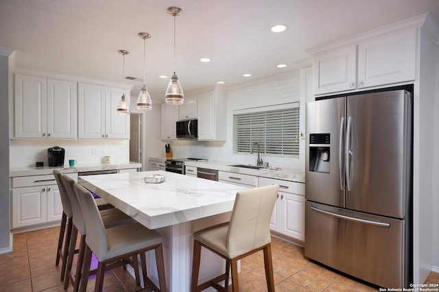 kitchen with white cabinets, appliances with stainless steel finishes, a center island, and sink