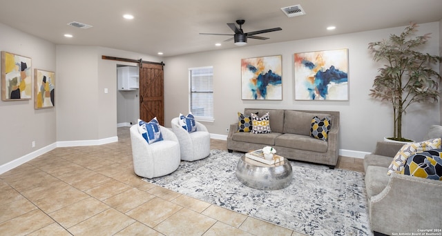 living room with light tile patterned floors, a barn door, and ceiling fan