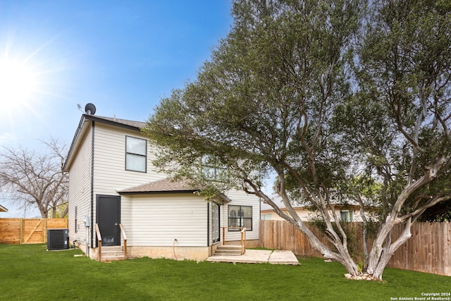 rear view of property featuring a yard, central AC, and a patio area