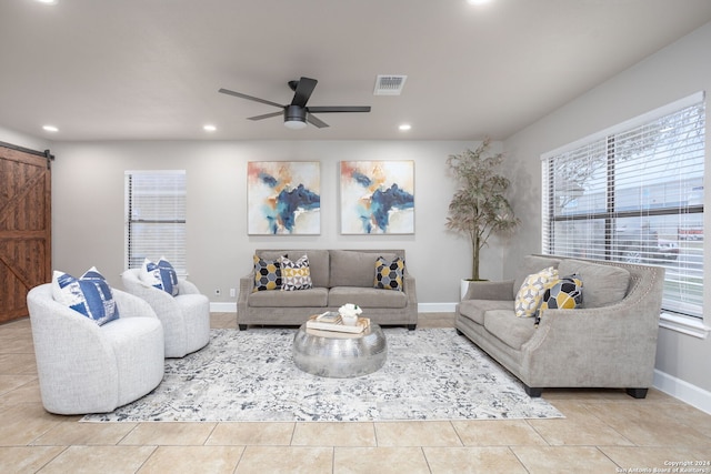 living room featuring a barn door, ceiling fan, and light tile patterned floors