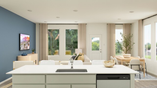 interior space featuring dishwashing machine, sink, a center island with sink, light hardwood / wood-style flooring, and white cabinetry