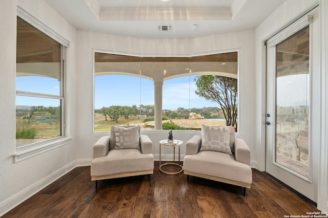 living area featuring dark hardwood / wood-style flooring, ornamental molding, and a tray ceiling