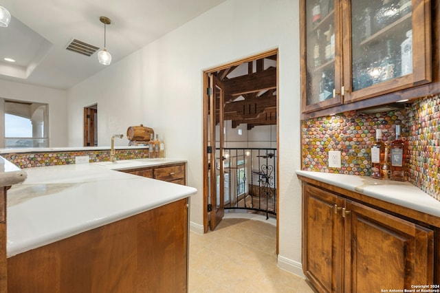 kitchen featuring sink, tasteful backsplash, kitchen peninsula, decorative light fixtures, and light tile patterned floors