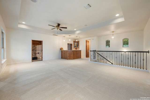 carpeted empty room featuring a tray ceiling and ceiling fan