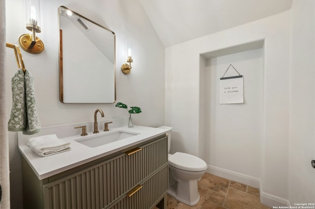 bathroom with vanity, toilet, and lofted ceiling