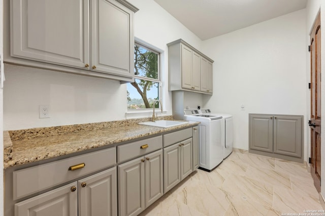 clothes washing area with cabinets, separate washer and dryer, and sink