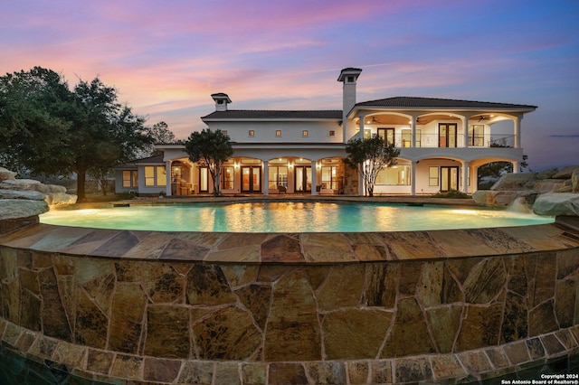 pool at dusk featuring pool water feature