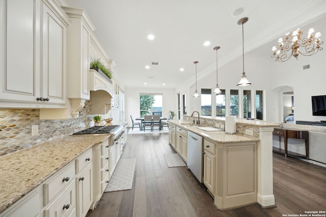 kitchen with appliances with stainless steel finishes, light stone counters, sink, dark hardwood / wood-style floors, and hanging light fixtures