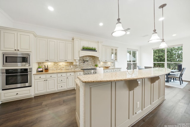 kitchen featuring cream cabinetry, appliances with stainless steel finishes, dark hardwood / wood-style floors, and hanging light fixtures