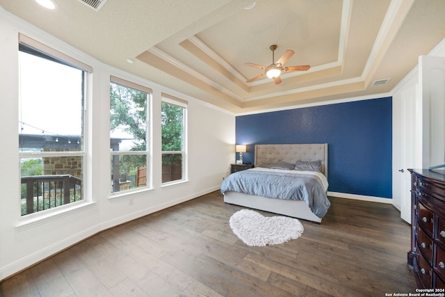 bedroom featuring ceiling fan, a raised ceiling, dark wood-type flooring, and crown molding