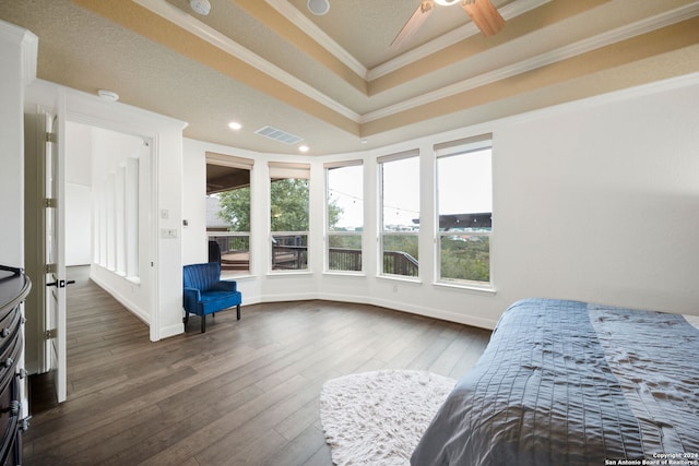 bedroom featuring ceiling fan, dark hardwood / wood-style flooring, ornamental molding, and a tray ceiling