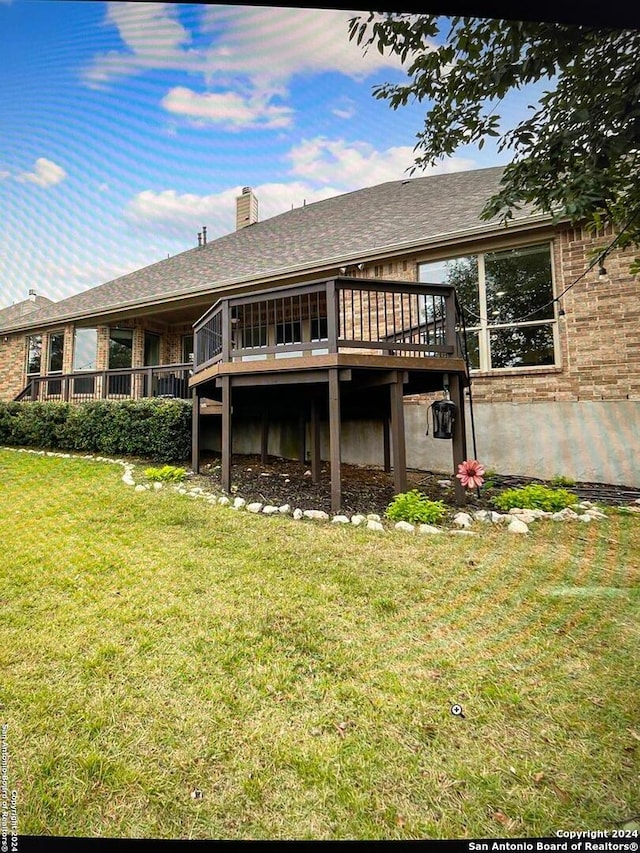 rear view of house featuring a deck and a yard