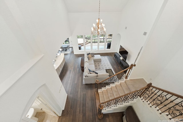 living room with hardwood / wood-style floors, ornamental molding, a notable chandelier, and a high ceiling