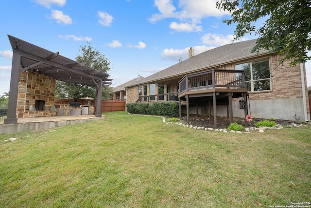 view of yard with an outdoor stone fireplace, a pergola, a deck, and exterior kitchen