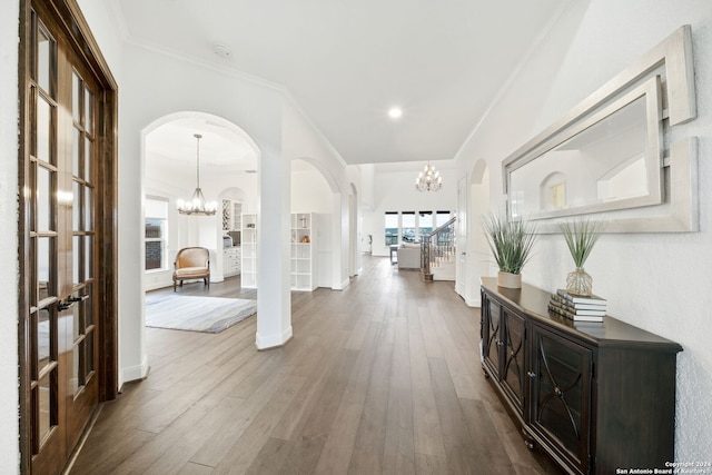 entrance foyer featuring hardwood / wood-style floors, french doors, crown molding, and a chandelier