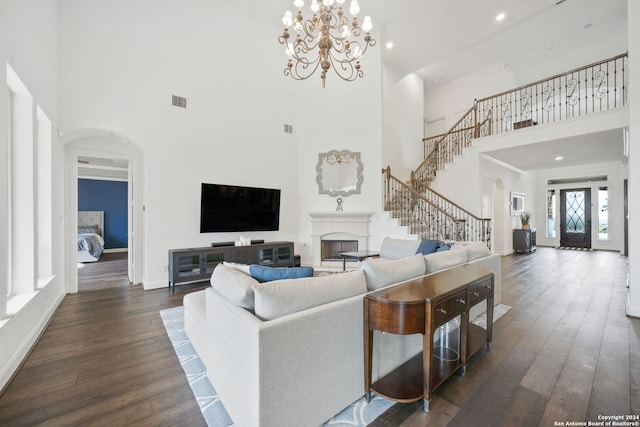 living room featuring a towering ceiling, dark wood-type flooring, and a notable chandelier