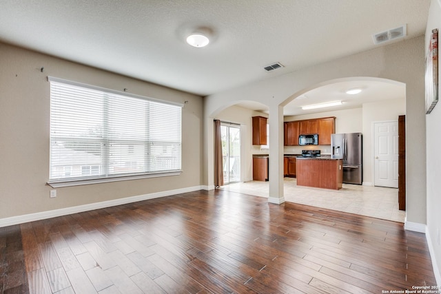 unfurnished living room featuring light hardwood / wood-style floors and a textured ceiling