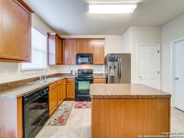 kitchen featuring sink, a kitchen island, black appliances, and light tile patterned floors