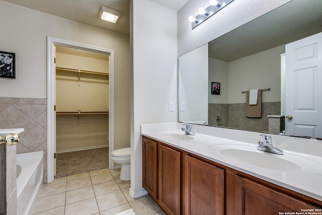 bathroom with vanity, a bathtub, tile patterned flooring, toilet, and tile walls