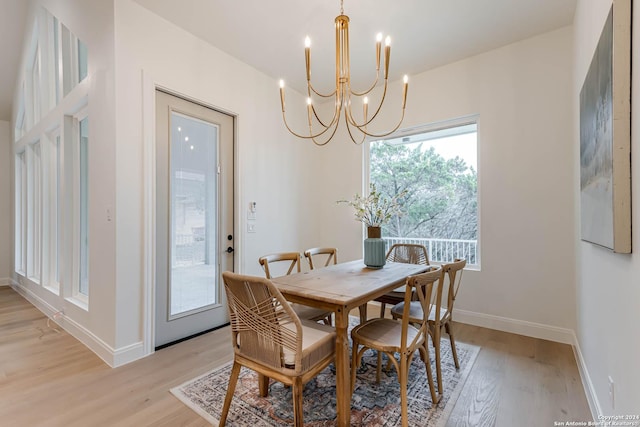 dining area with light wood-type flooring and an inviting chandelier