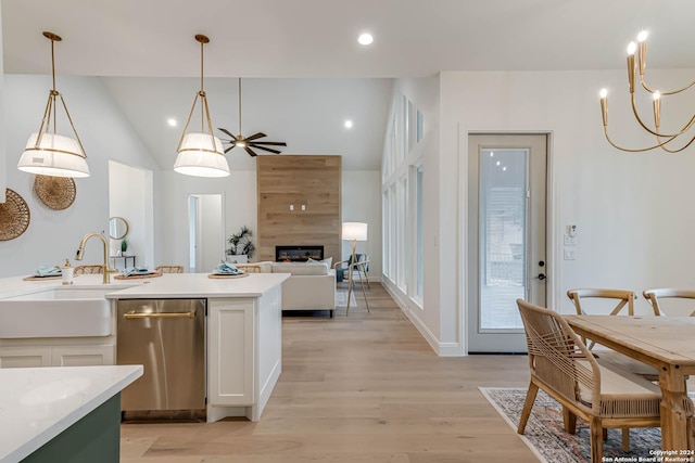 kitchen with pendant lighting, white cabinets, sink, light wood-type flooring, and a large fireplace