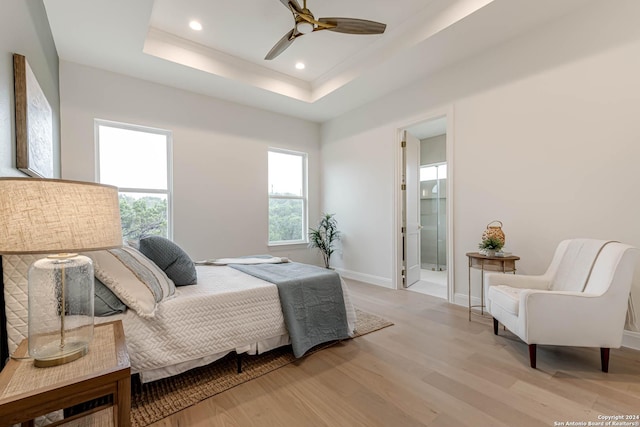 bedroom featuring connected bathroom, light hardwood / wood-style floors, a raised ceiling, and ceiling fan