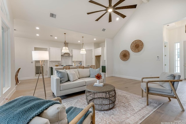 living room with ceiling fan, light hardwood / wood-style floors, and high vaulted ceiling