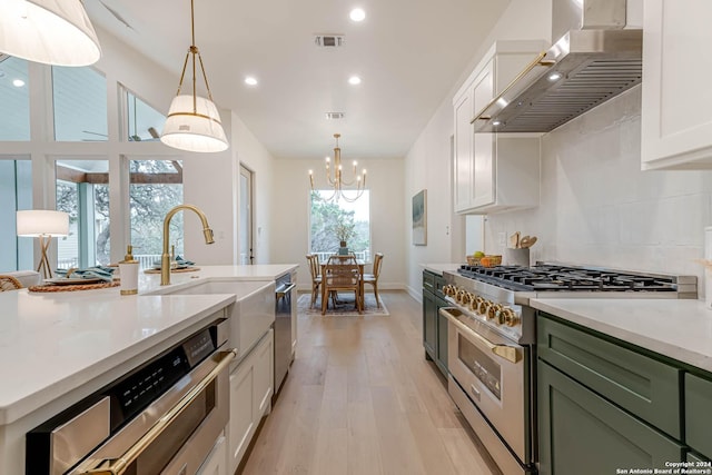 kitchen with light wood-type flooring, stainless steel appliances, a healthy amount of sunlight, and wall chimney range hood