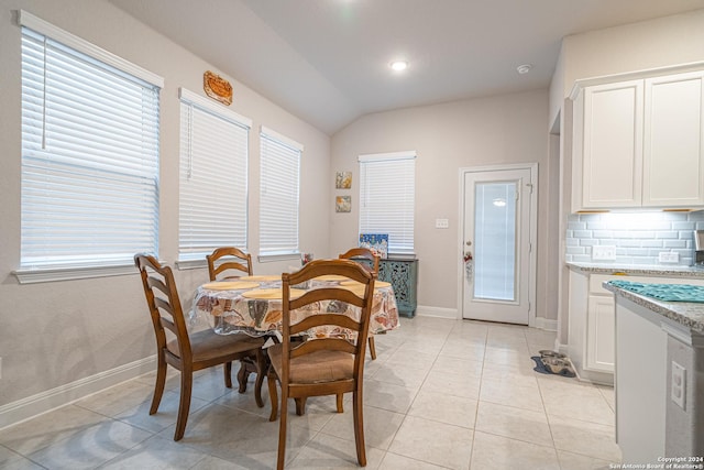 dining room with a wealth of natural light, light tile patterned flooring, and vaulted ceiling