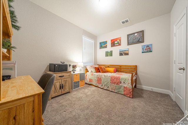 bedroom with a textured ceiling and light colored carpet